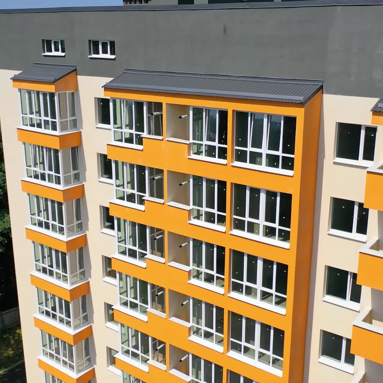 Modern office building in the city. Exterior of a new apartment building with colorful walls and large balconies. Top down drone movement