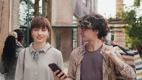 boyfriend and girlfriend walking outdoor with shopping bags and chatting