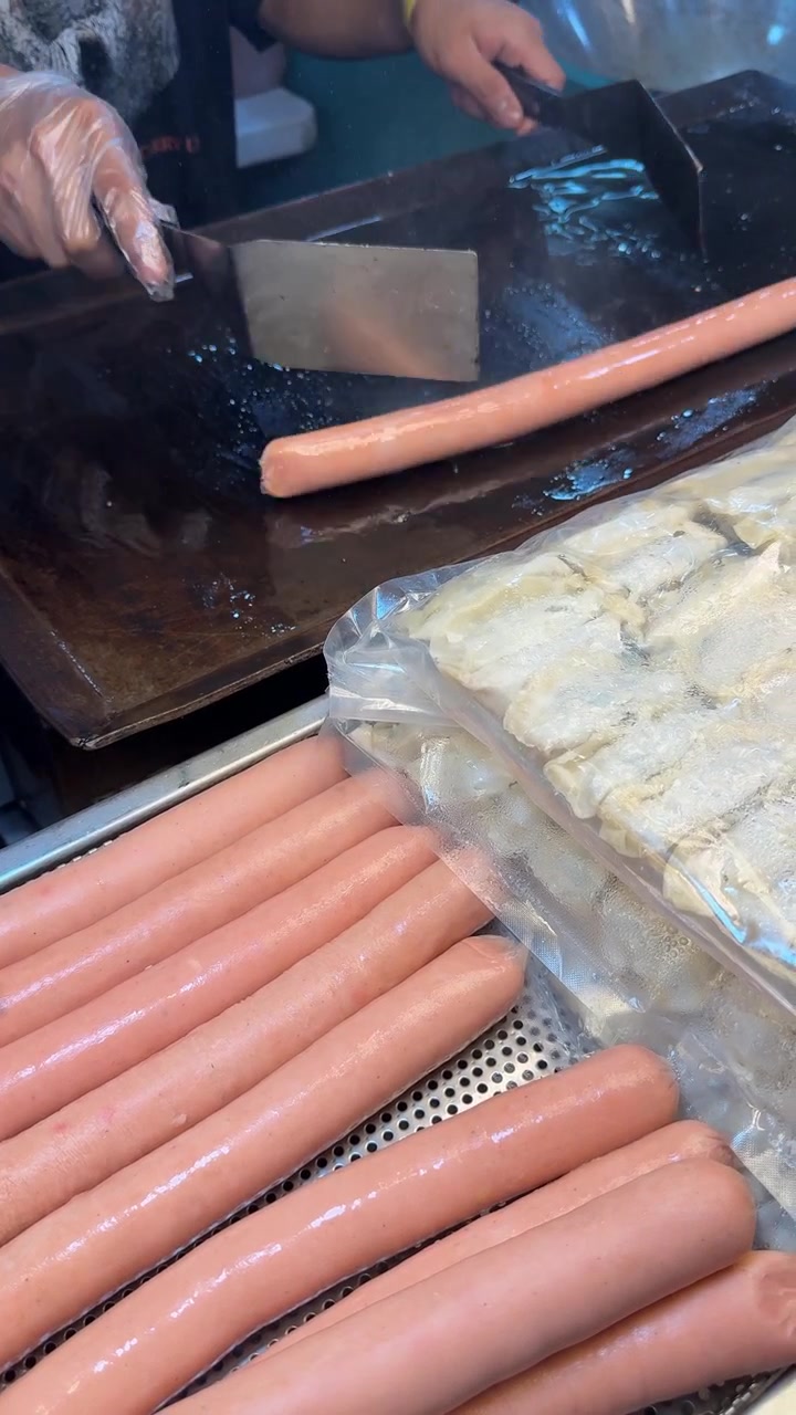 Street Food Vendor Grilling Sausages on a Hot Flat Top Grill