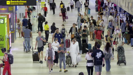 a bustling scene of the arrival area at don mueang airport, filled with tourists from various countries, excited for their thai holiday. great for travel, tourism, and airport-related content.