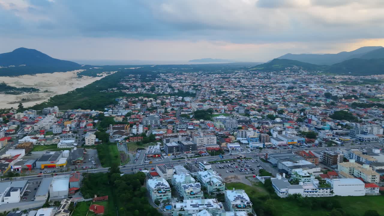 Quang cảnh toàn cảnh từ trên không của khu dân cư và các dãy nhà đô thị ở Ingleses, Florianopolis, Brazil, với cồn cát và đồi núi tại Santa Catarina, làm phông nền cho căn hộ.