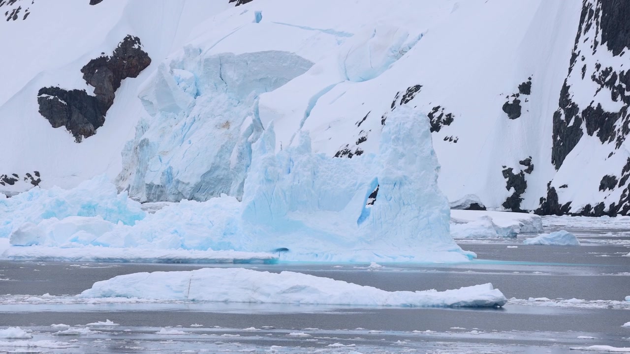 Iceberg perto de montanha coberta de neve visto durante passeio de barco, Antártica. Em tempo real.