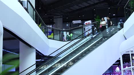 people ascending an escalator in a mall