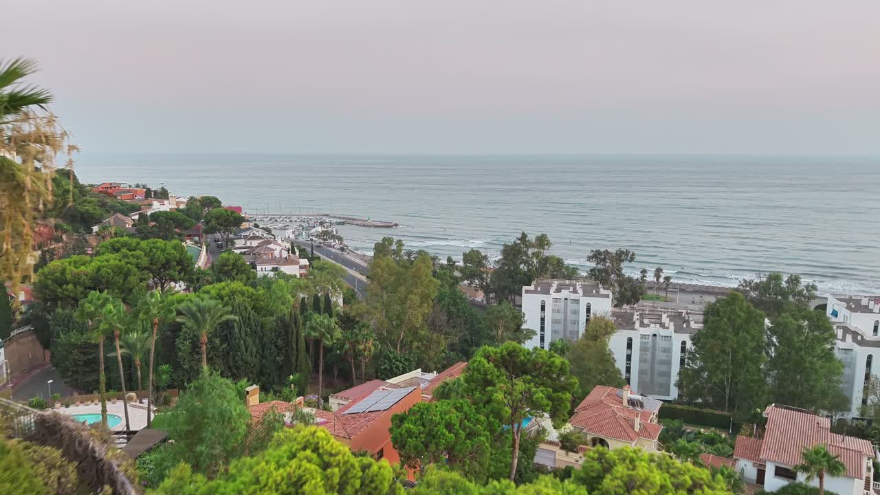 Smooth drone dolly shot forward above Málaga hillside homes toward the calm sea view