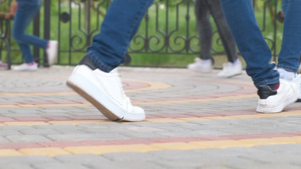 piernas femeninas vestidas con vaqueros y zapatillas de deporte en un círculo una por una