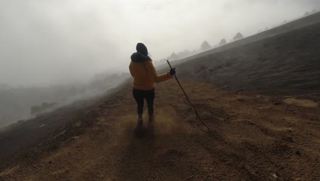 following pov: woman runs, glissades down foggy ash slope of volcano