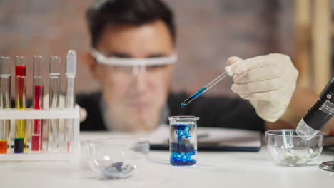 un científico experto agrega líquido azul al agua clara en la prueba