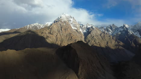 cinematic drone shot of tupopdan peak, passu cones in hunza pakistan, snow covered mountain peaks with steep cliffs, high wide panning aerial shot