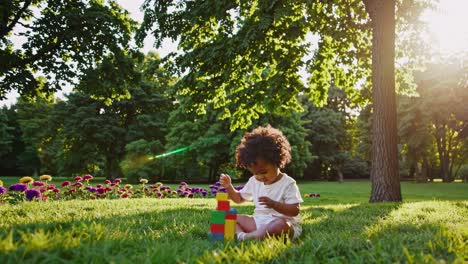 A child plays with colorful blocks in a sunlit park, captured from a low-angle, evoking a serene