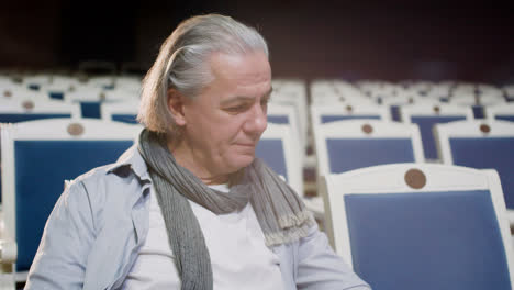 alter mann sitzt auf seinem sitz am teather