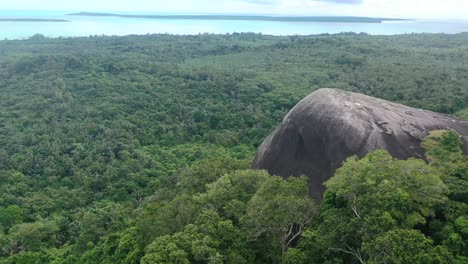 giant boulder batu baginda surrounded by dense forest