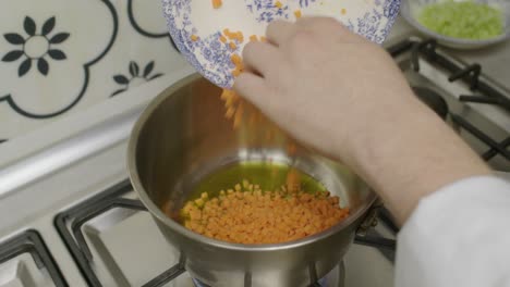 el chef agrega zanahorias picadas en una olla de metal con aceite de oliva