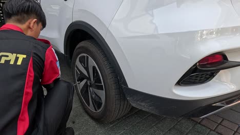 person in uniform examining a vehicle's wheel