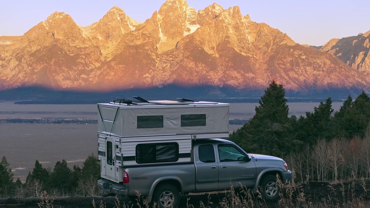 Truck camper with goldenhour alpenglow light on Grand Teton mountain range behind