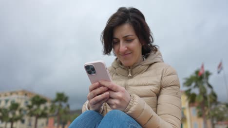 mujer sentada hablando y escribiendo en un teléfono móvil