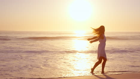 free happy woman spinning arms outstretched enjoying nature dancing on beach at sunset slow motion red dragon