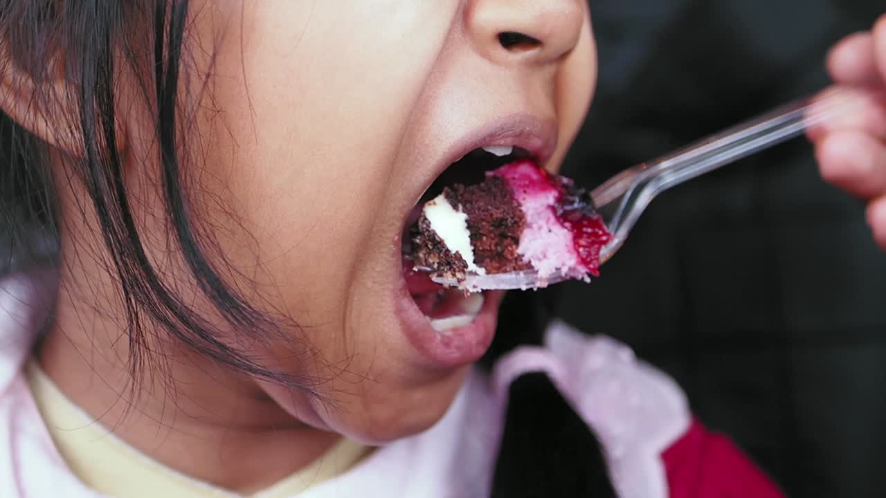 Close up of a young girl eating a slice of cake