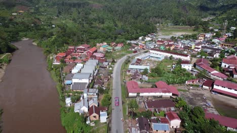 pink bus drives through village, town city, of madagascar jungle