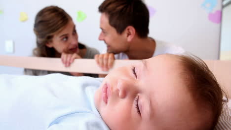 Happy-parents-watching-over-baby-son-in-crib-