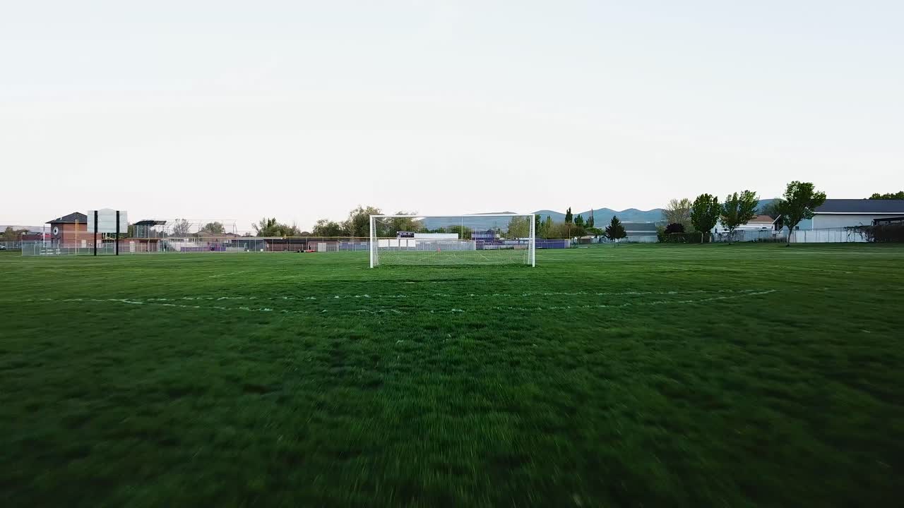サッカー場をゴールに向かってスムーズに飛行する4kワイドドローンショット