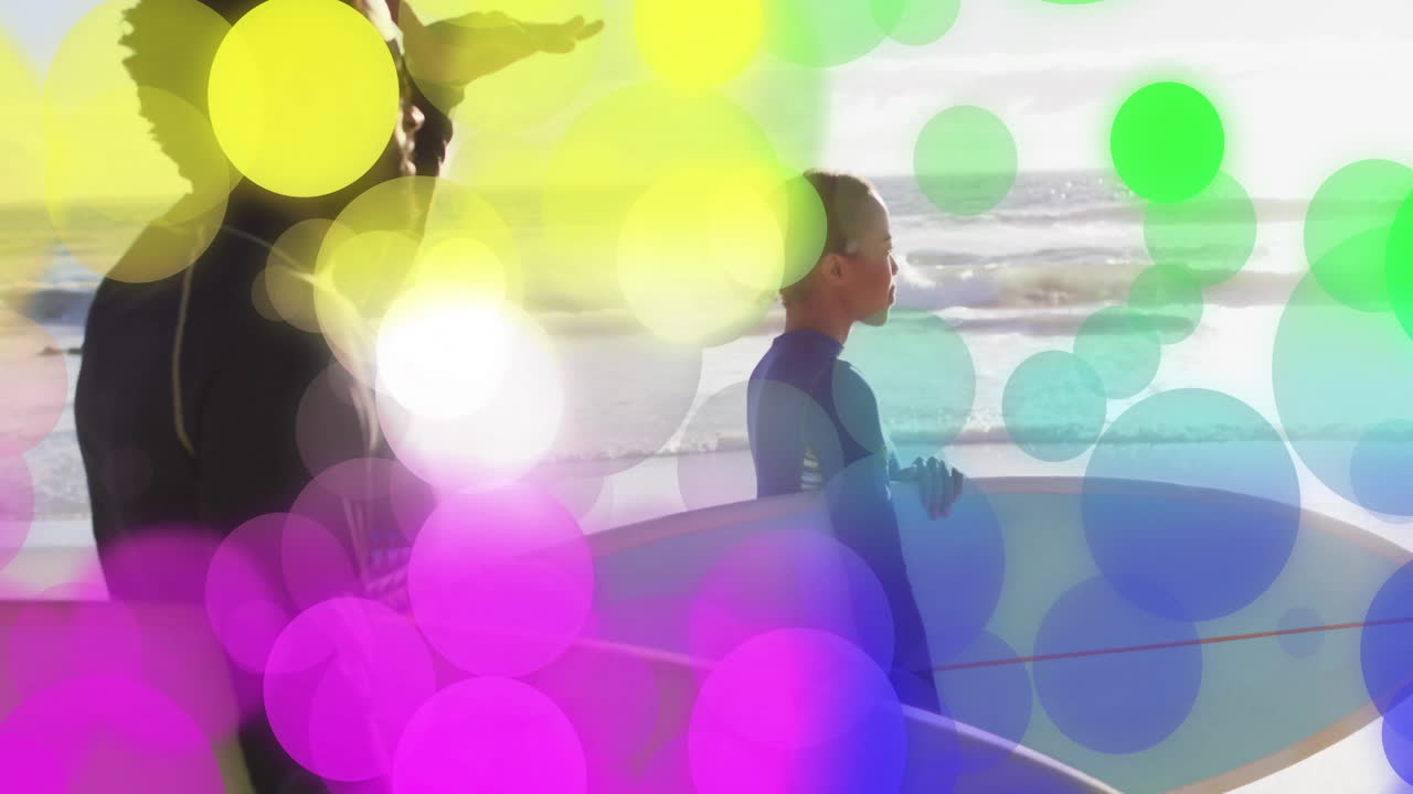 Two surfers standing holding surfboards on sandy beach, with animated bokeh lights promoting health