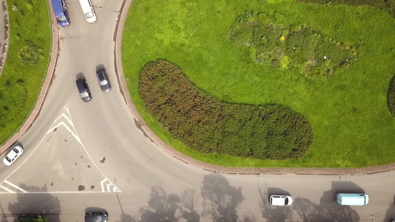 vista aérea de arriba hacia abajo de la intersección de la calle de la rotonda con el tráfico de coches en movimiento.