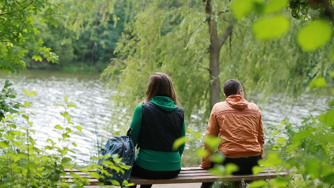 Beautiful young couple sitting on a bench in the park