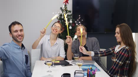 Emocionados-Colegas-De-Oficina-Celebrando-La-Fiesta-Corporativa-Navideña,-Saludando-Con-Destellos-Dorados