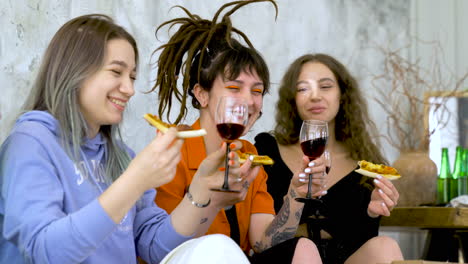 happy female friends eating pizza and toasting with wine at home