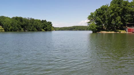 Un-Dron-De-Bajo-Vuelo-Pasa-Sobre-Un-Lago-En-Un-Campo-Rural