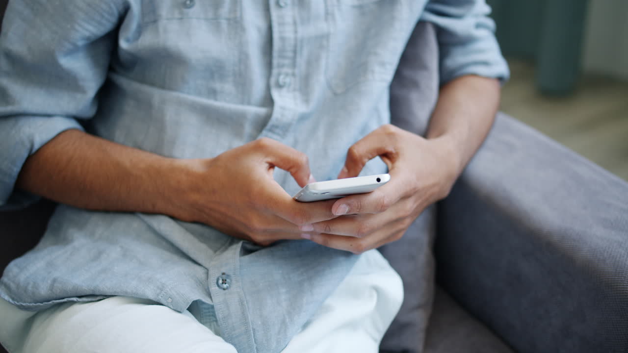 소파에서 스마트폰을 사용하는 남자