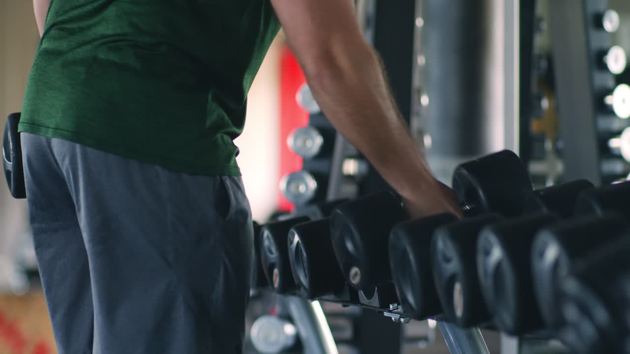 체육관 에서 덤벨 을 들어 올리는 남자