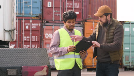 baas en werknemer organiseren een vrachtwagenpark in een logistiek park terwijl ze een document raadplegen 2