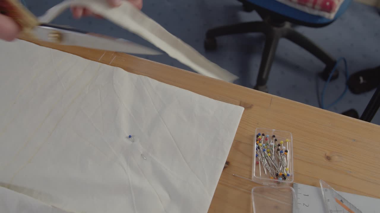 An overview of scissors cutting out bands from fabric and discarding the excess material