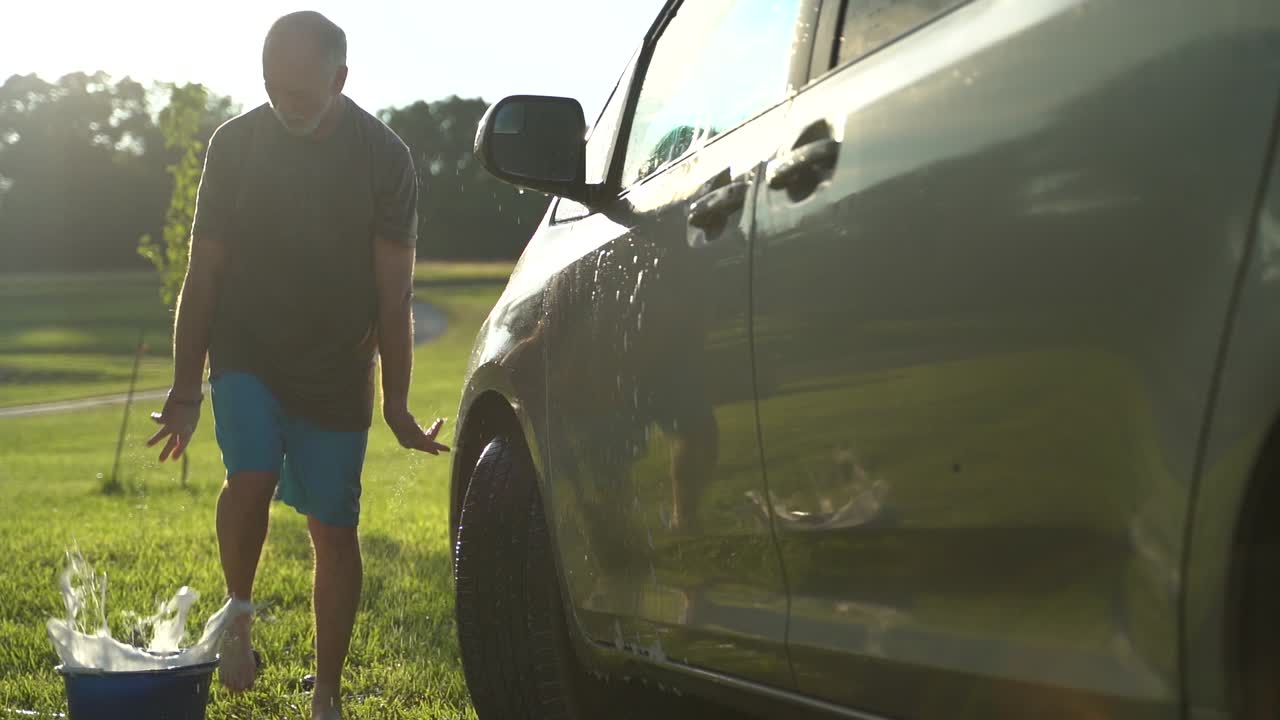 hombre gracioso bailando lavando auto con sol retroiluminado en cámara lenta