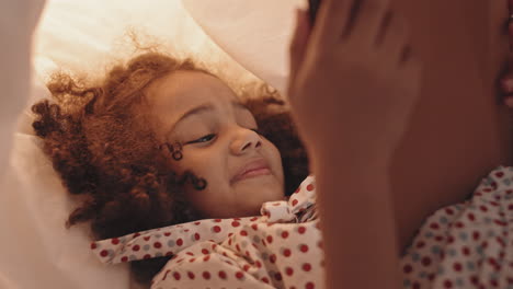 mixed-race girl using tablet in pillowfort