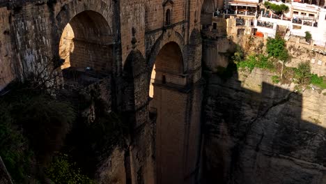 Die-Atemberaubende-Alte-Backsteinbrücke-Steht-In-Der-Einsamkeit-Der-Schatten-In-Ronda,-Spanien