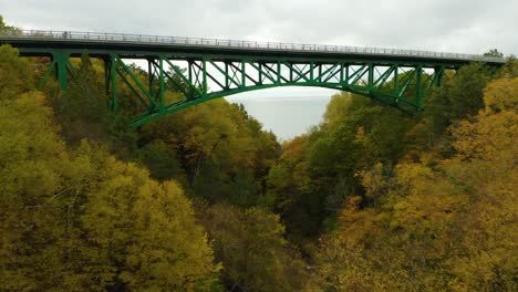 Drohne-Fliegt-In-Richtung-Grüne-Brücke-Mit-Bunten-Blättern-Auf-Bäumen