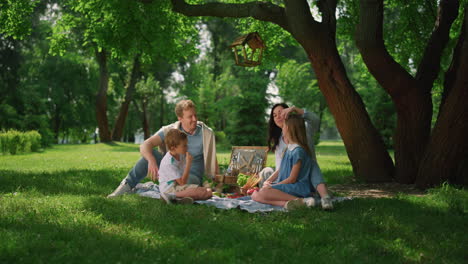 happy family enjoy picnic in summer park. cheerful people lunching on grass.