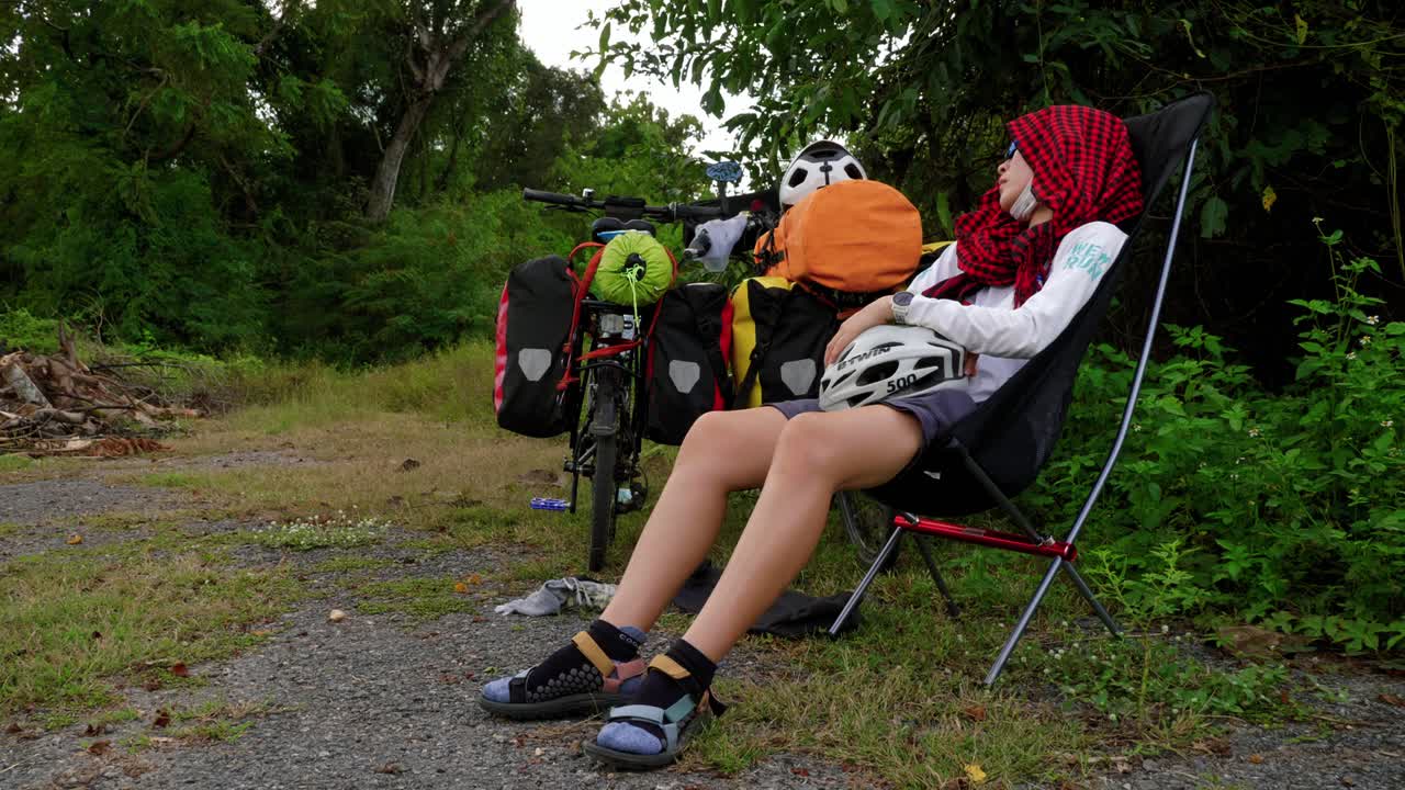 ciclista femenina descansando en una silla con casco después de un día de andar en bicicleta, tailandia