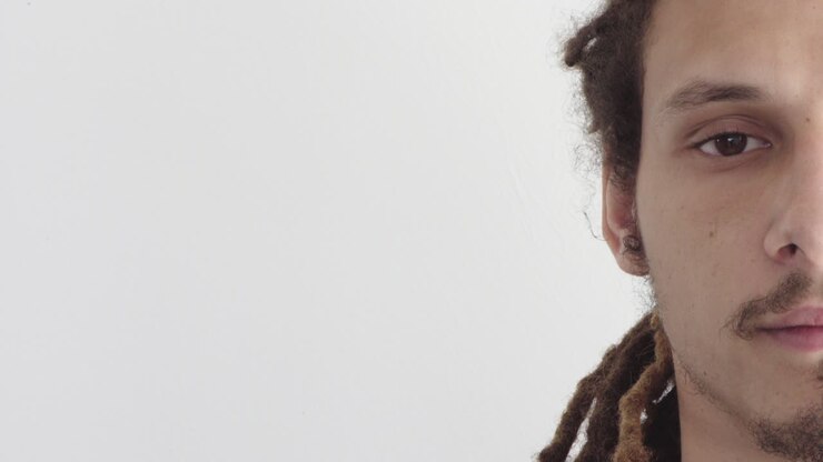 close up half face young mixed race man looking serious wearing dreadlocks hairstyle half face on white background
