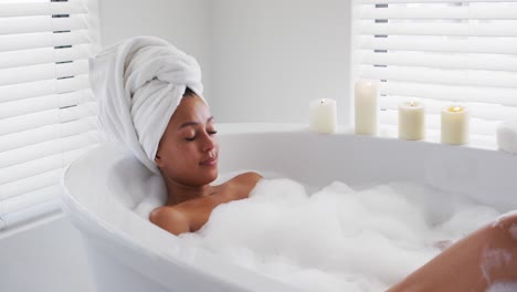 african american woman relaxing in the bath tub in the bathroom at home