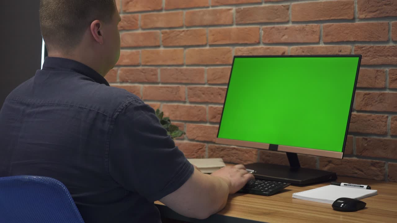 hombre trabaja en la computadora personal con pantalla de maqueta verde en la oficina
