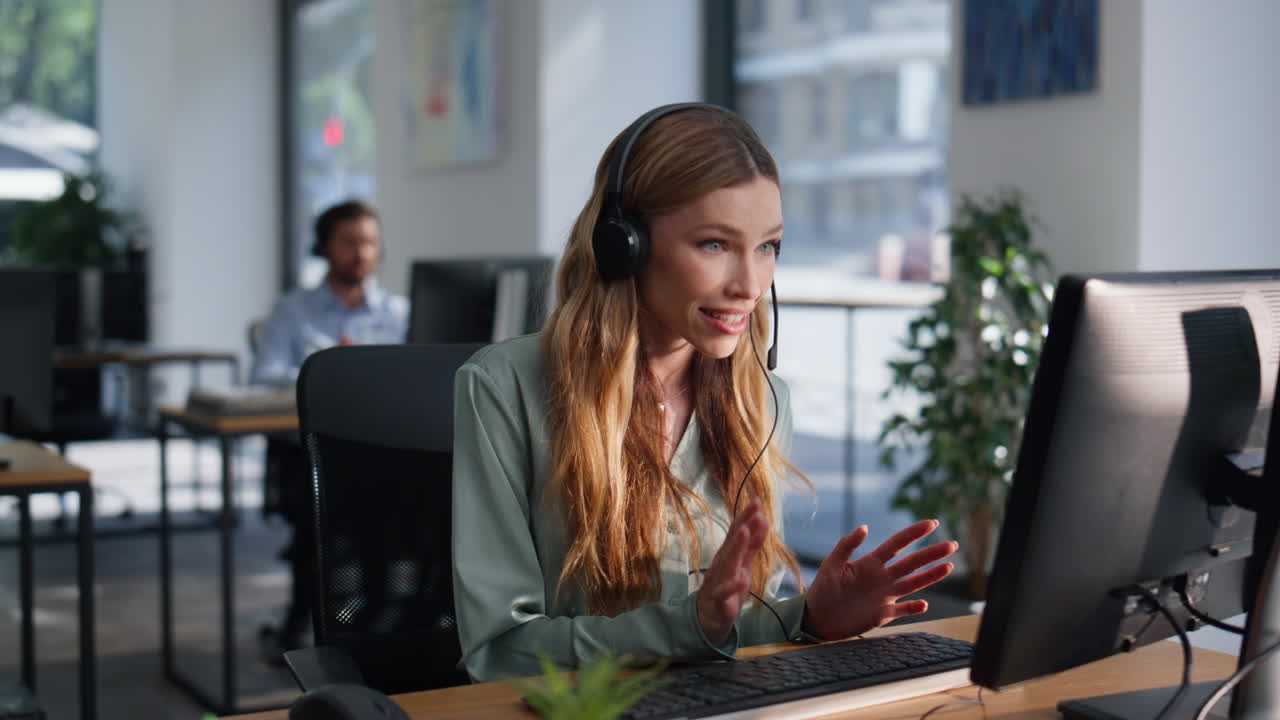 Primo piano di un consulente con cuffie che assiste un cliente mentre guarda i dati su un computer in ufficio