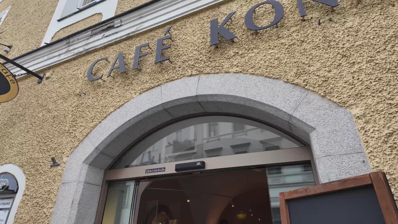 Passau sweet and chocolate manufacture with cafe and people sitting outside near the street, with indoor view. Cafe Simon, Bavaria.