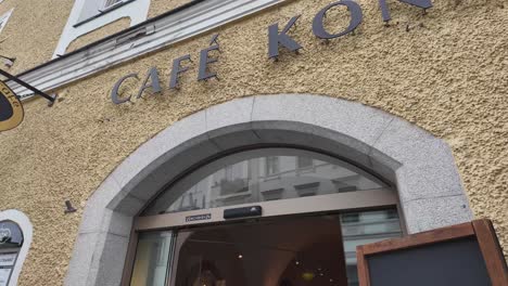 passau sweet and chocolate manufacture with cafe and people sitting outside near the street, with indoor view. cafe simon, bavaria.