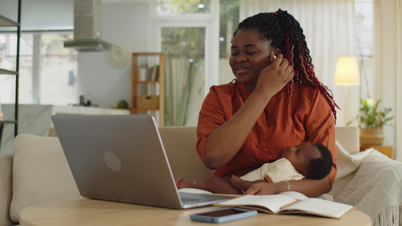 Businesswoman Having Online Meeting with Newborn Daughter in Hands