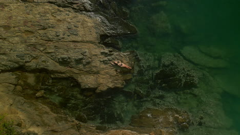 aerial view of person relaxing on rocks by the shore