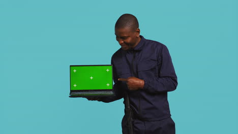 Portrait-of-happy-security-guard-at-work-showcasing-green-screen-laptop