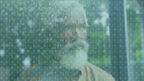 through rain-covered glass, elderly man with beard looking outside quietly